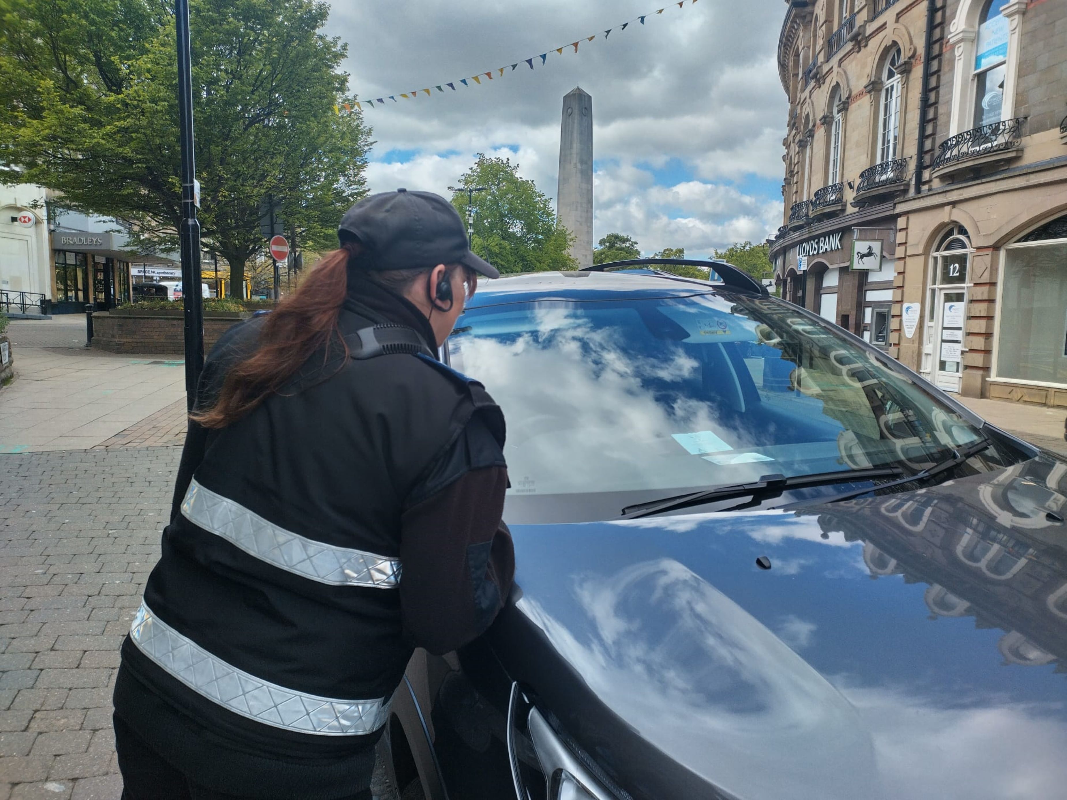A person looking at a blue badge on a car