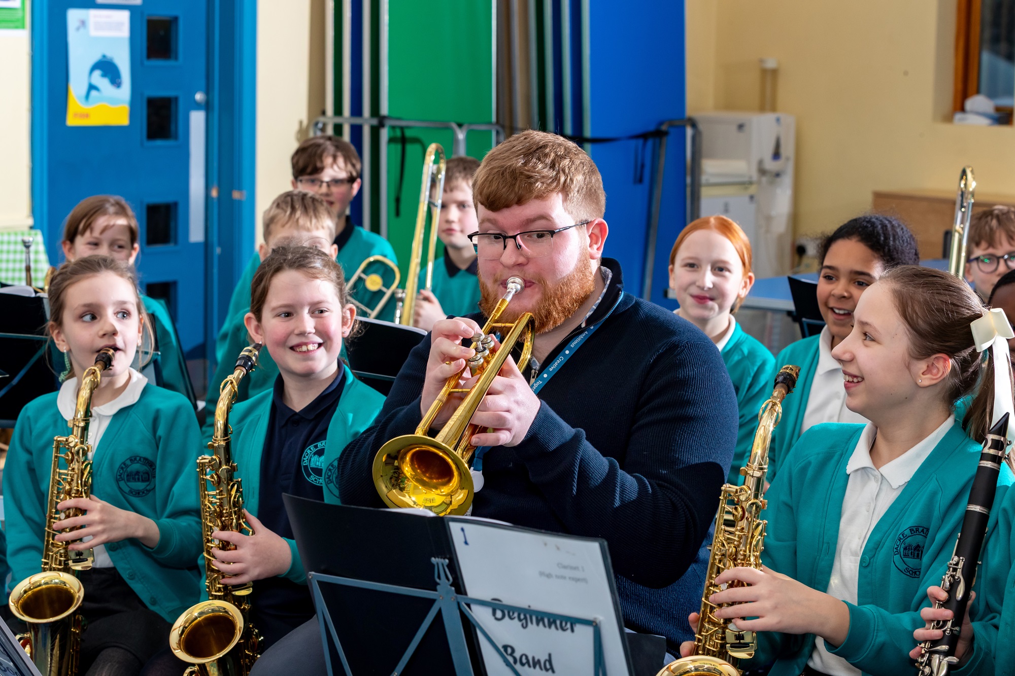 School band with their teacher sitting playing their instruments