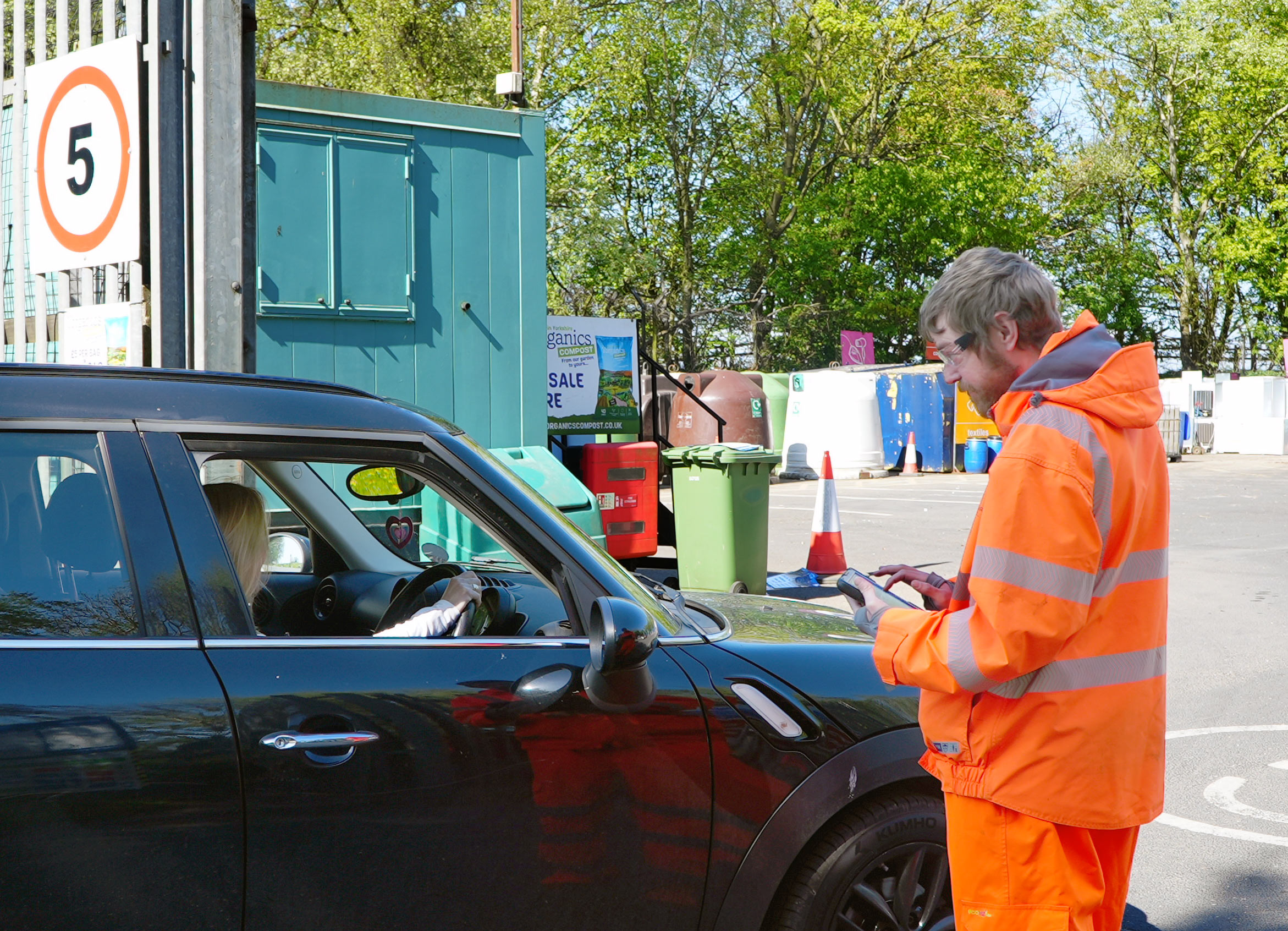 A man in hi viz checking car registration numbers at recycling centres