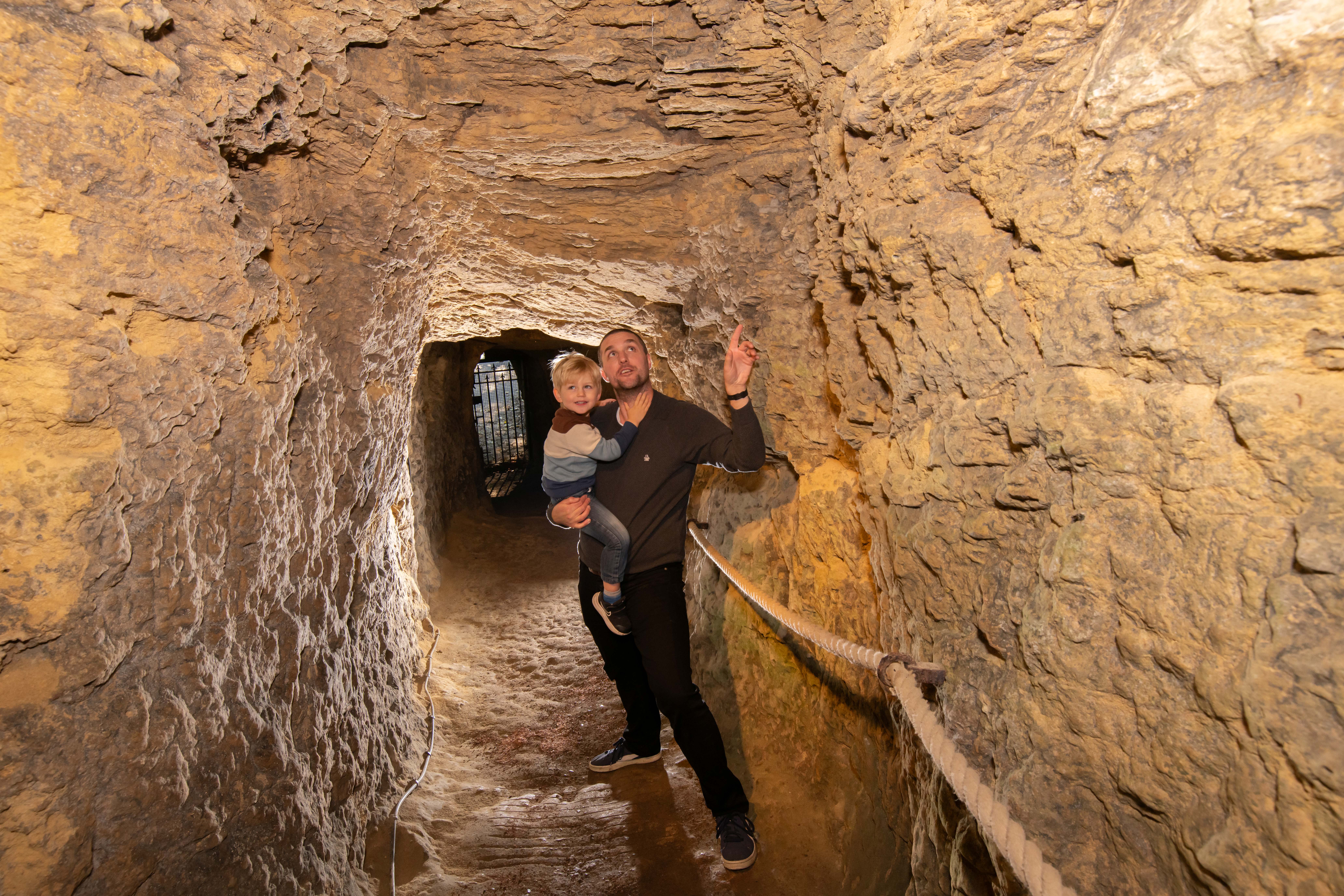 Adult holding a child in a secret underground medieval tunnel