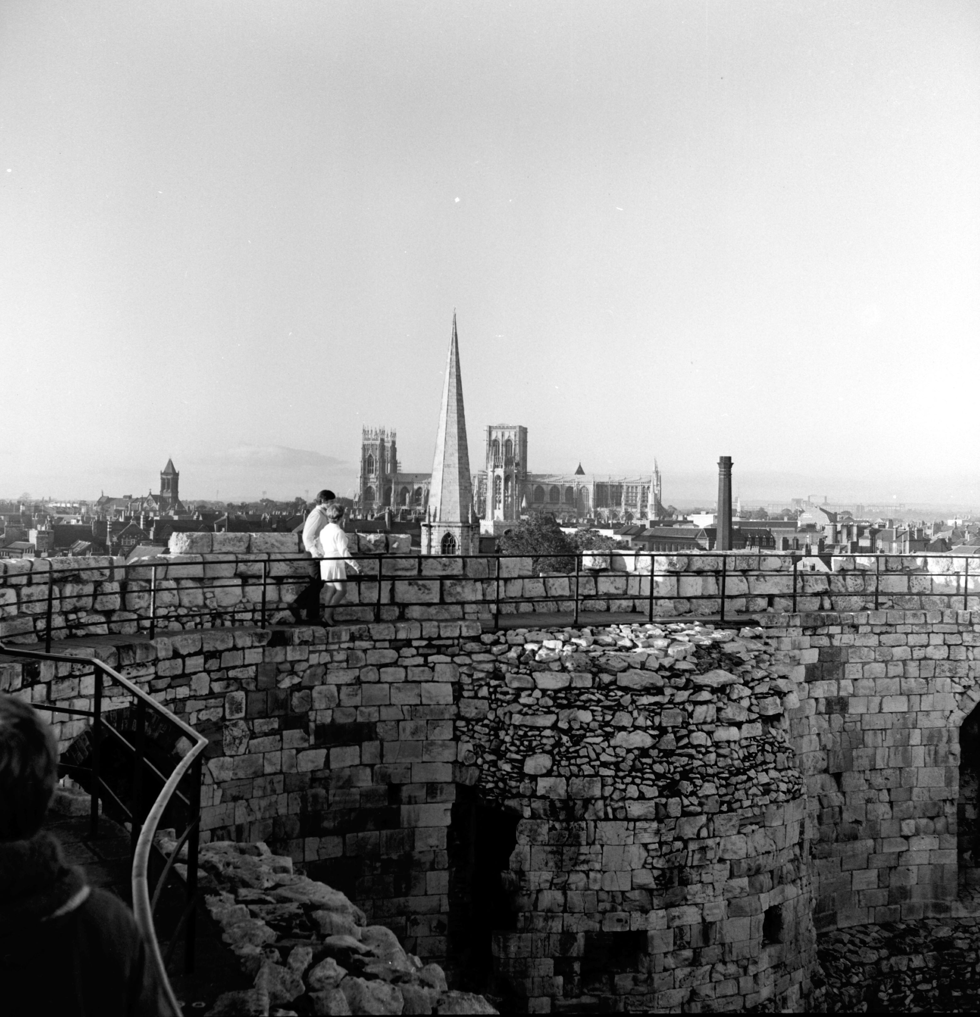 People on the walls of Clifford's Tower in York, with the city's Minster in the background. Taken by local photographer Bertram Unné, active between 1940 and 1979.