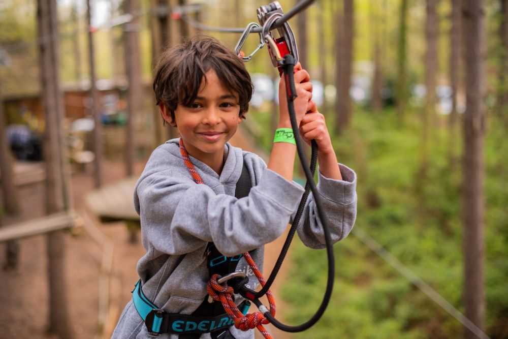 Child in a harness walking along a rope bridge at Go Ape