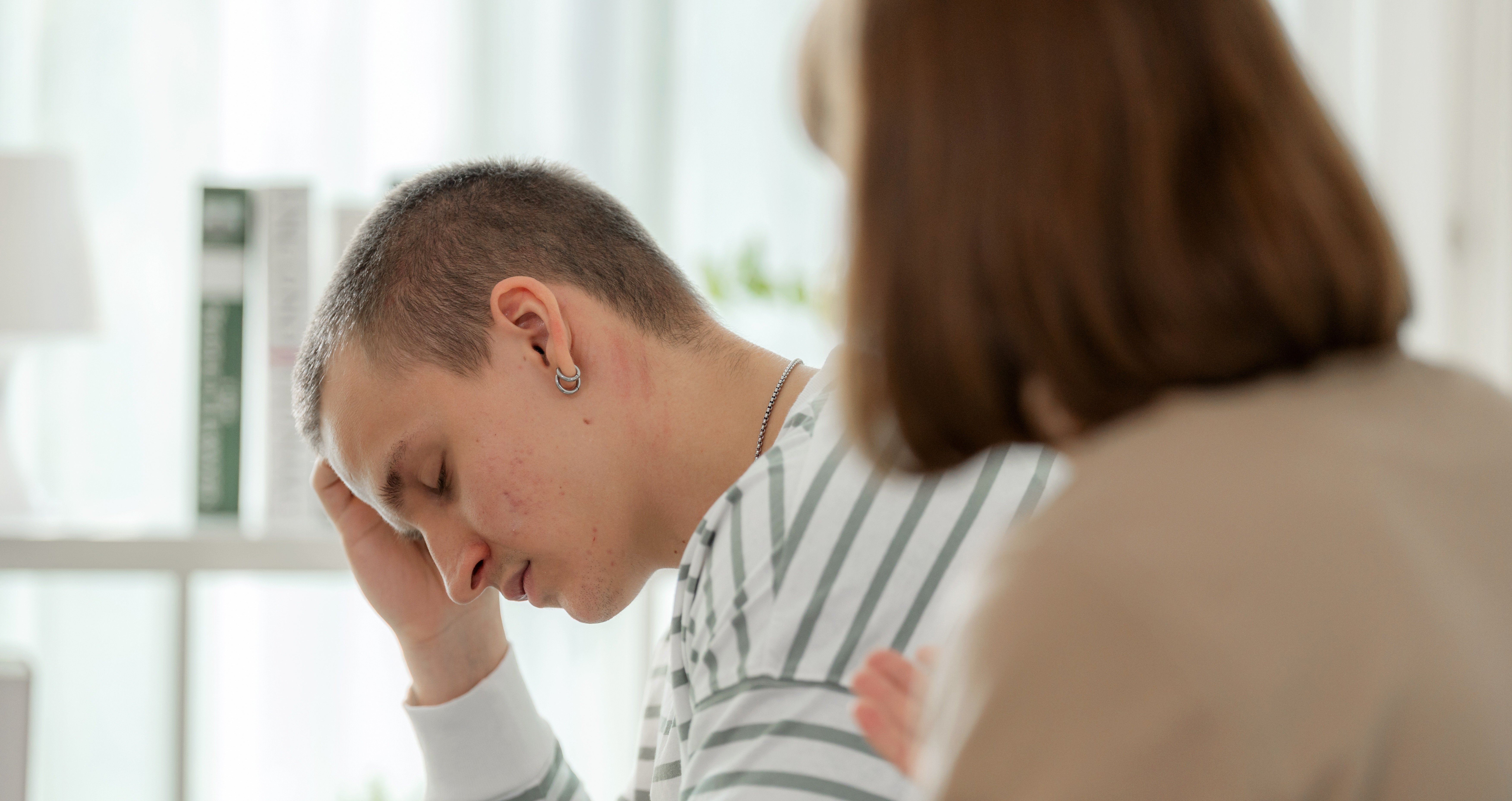 Person holding their head while someone talks to them