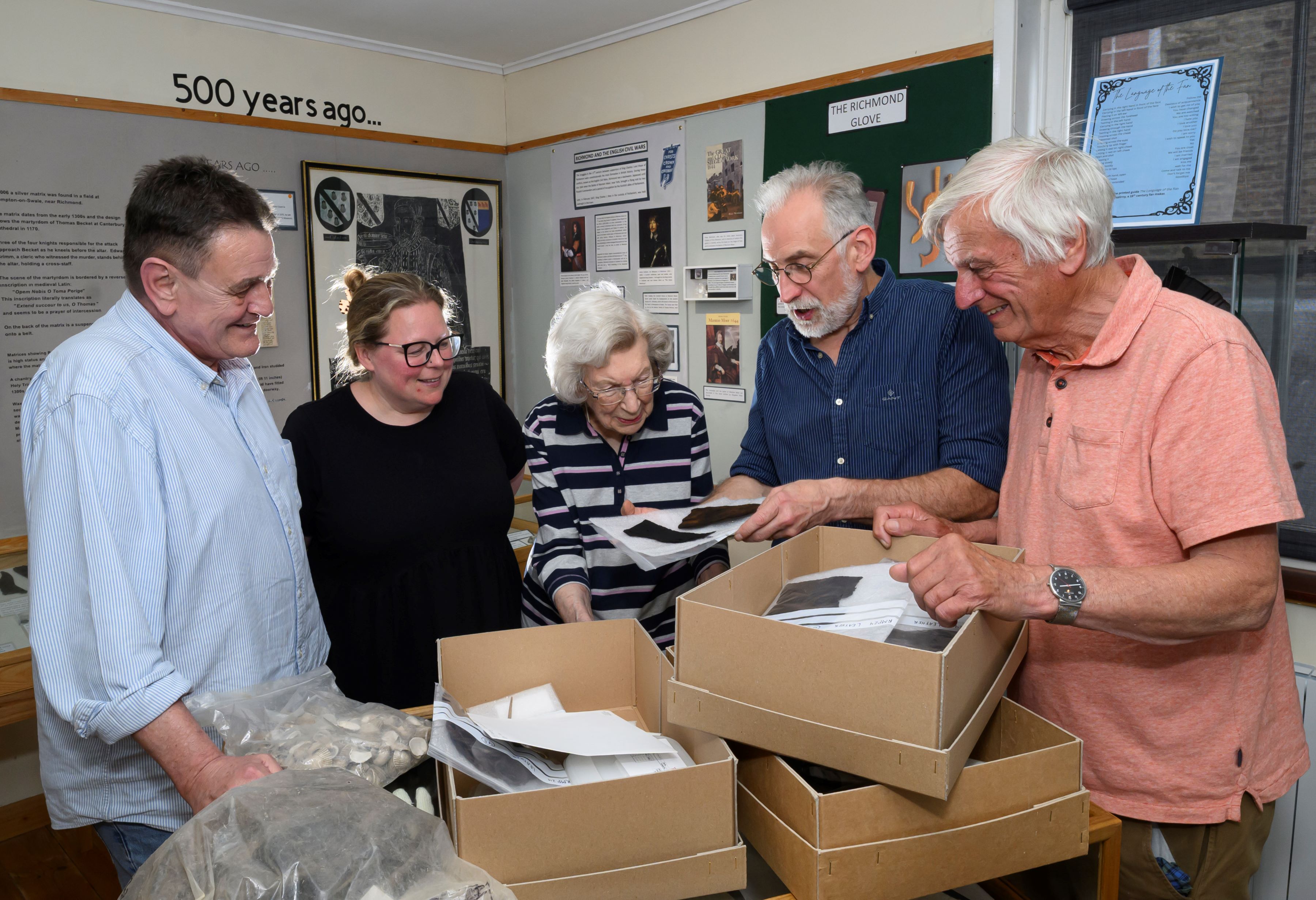 Four people looking at objects in a box