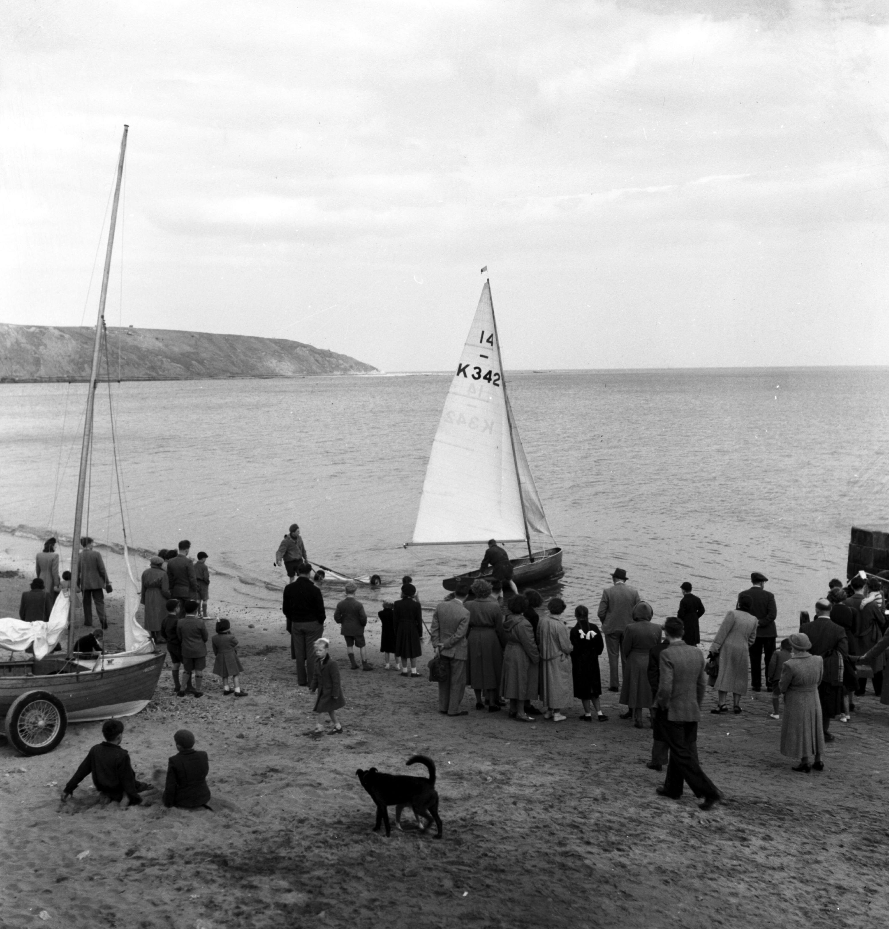 A crowd watches as a boat is launched in the sea at Filey.  Taken by local photographer Bertram Unné, active between 1940 and 1979.