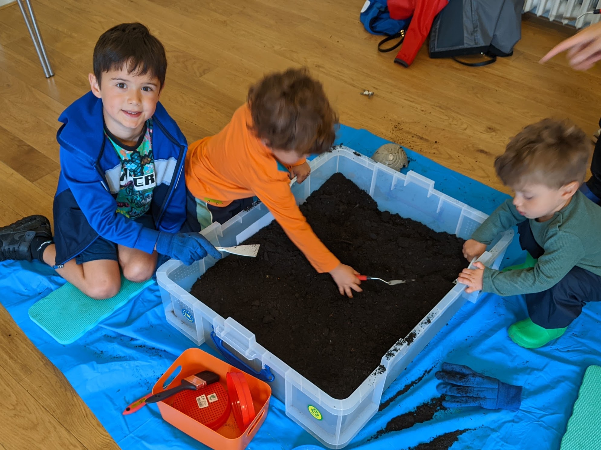 Three children sitting digging in soil