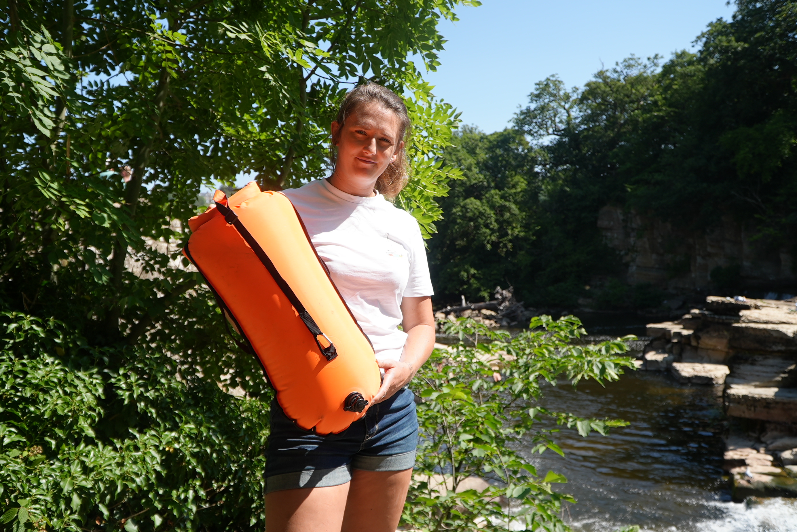 Jasmine Harrison standing by Richmond Falls holding an orange life saving device