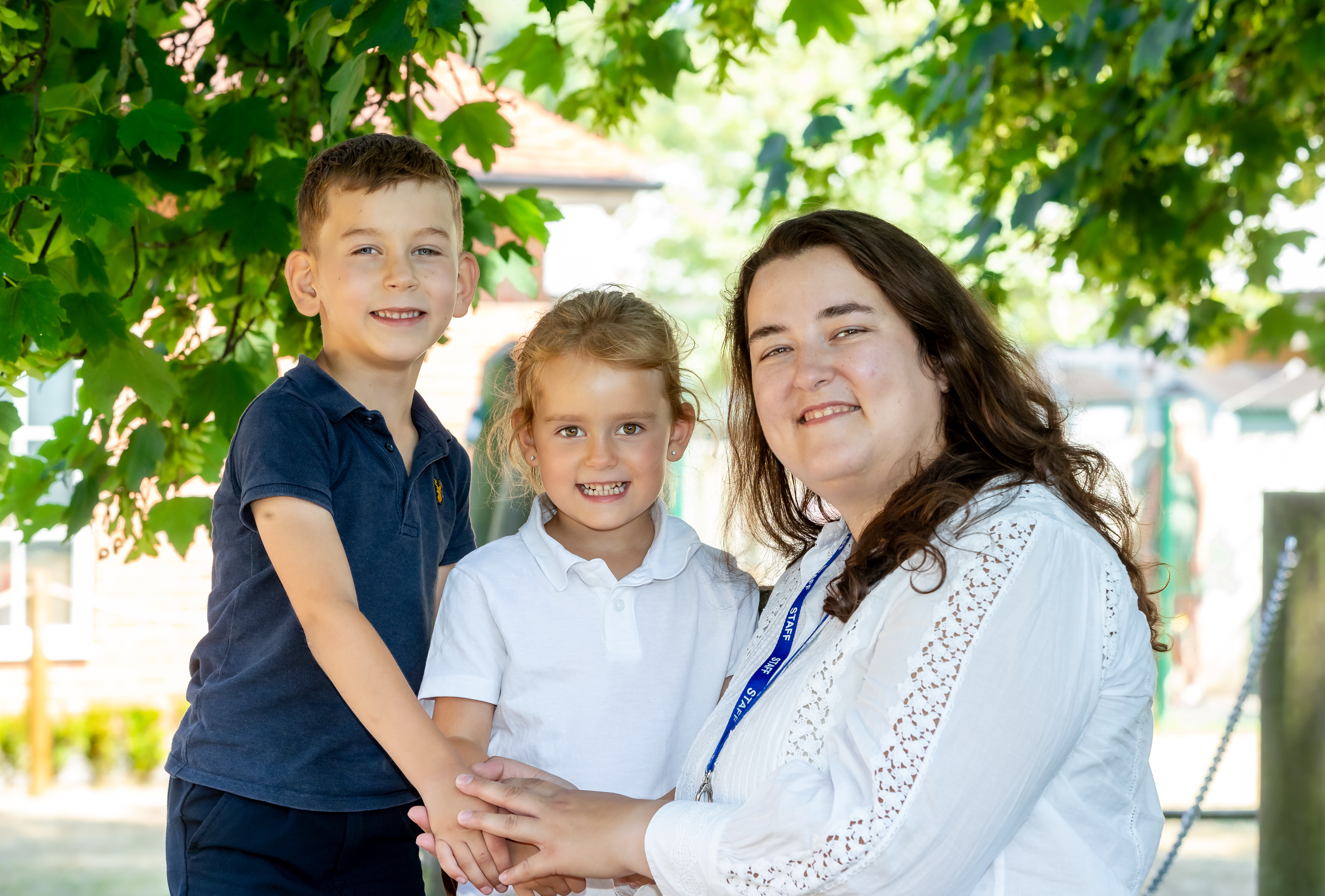 An adult with two young children outside smiling at the camera