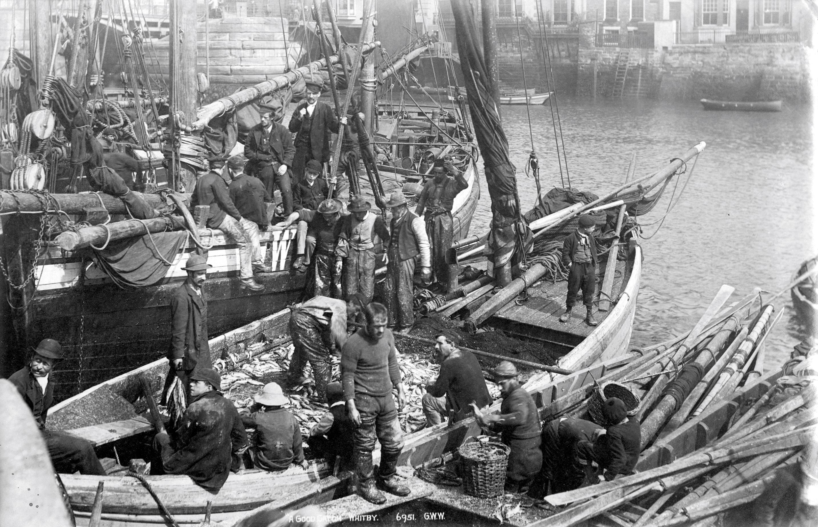 Fishing crews are pictured bringing their catch ashore at Whitby Harbour. The image is undated and was taken by G. W. Wilson & Co