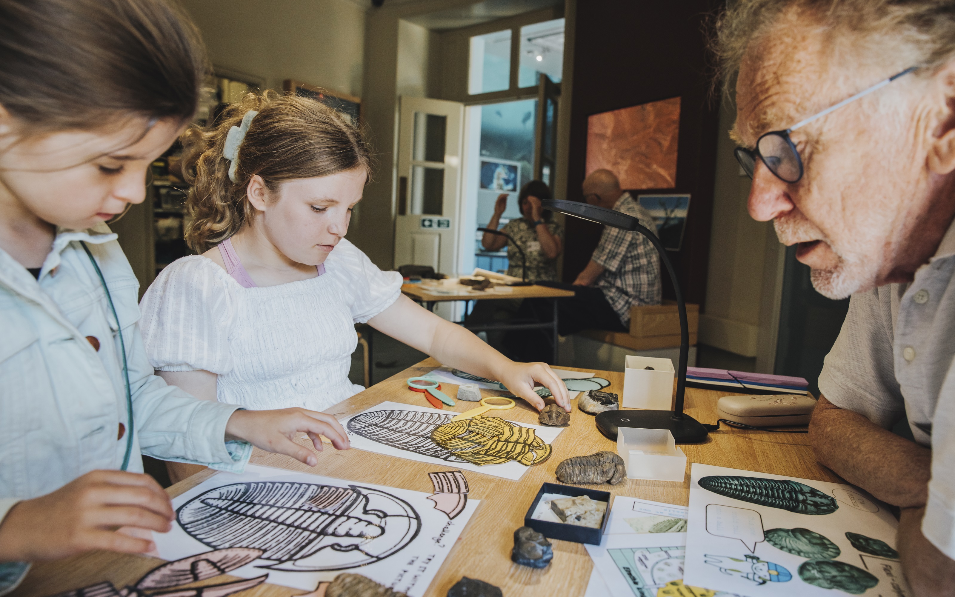 An adult and two children doing a dinosaur activity at a table