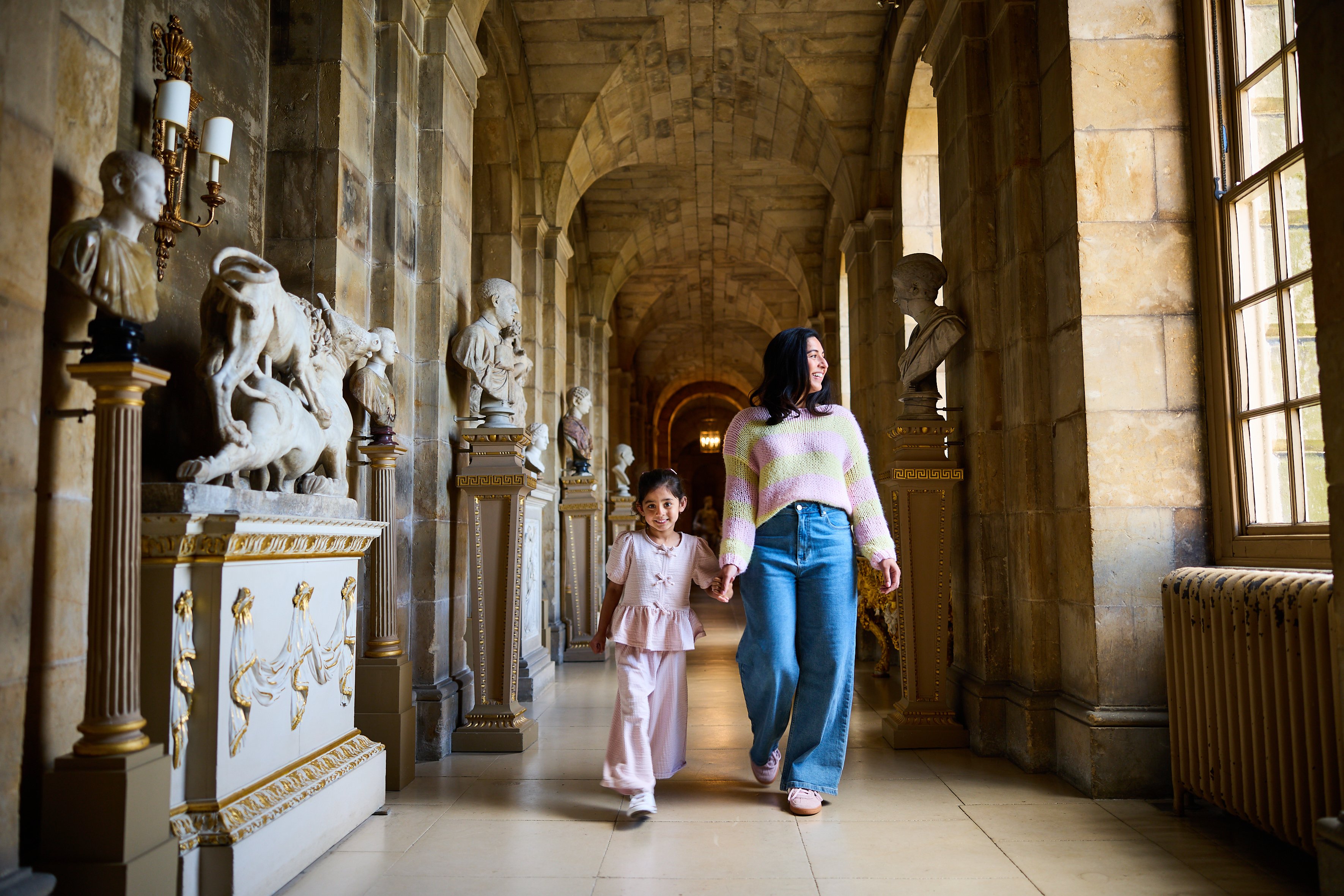 Adult and a child holding hands walking through Castle Howard
