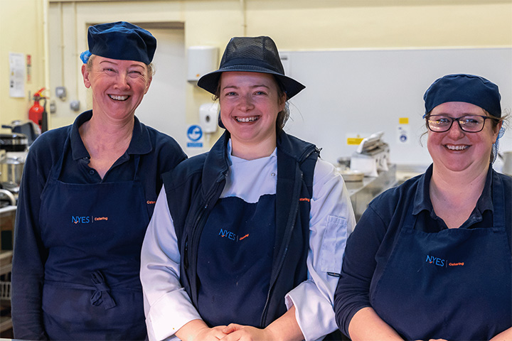 Three cooks smiling in school kitchen