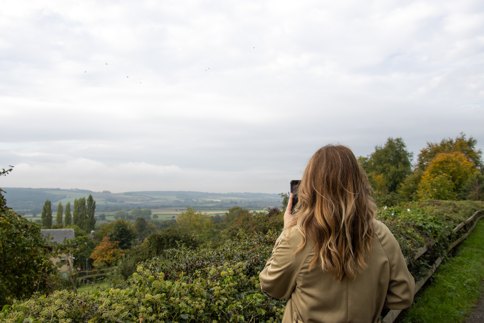 An adult taking a phone of the abbey in the distance