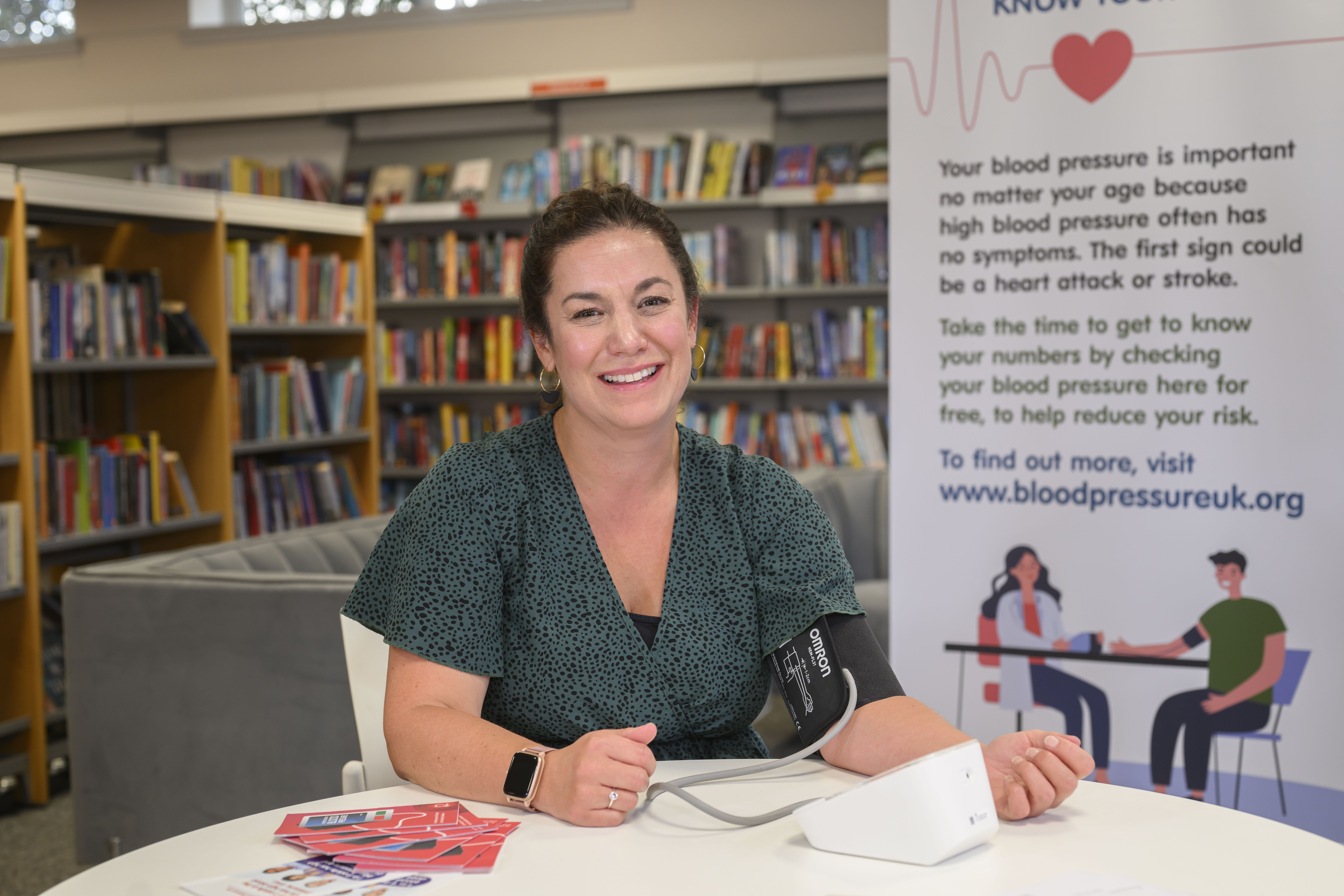 Adult sitting at a table having her blood pressure taken