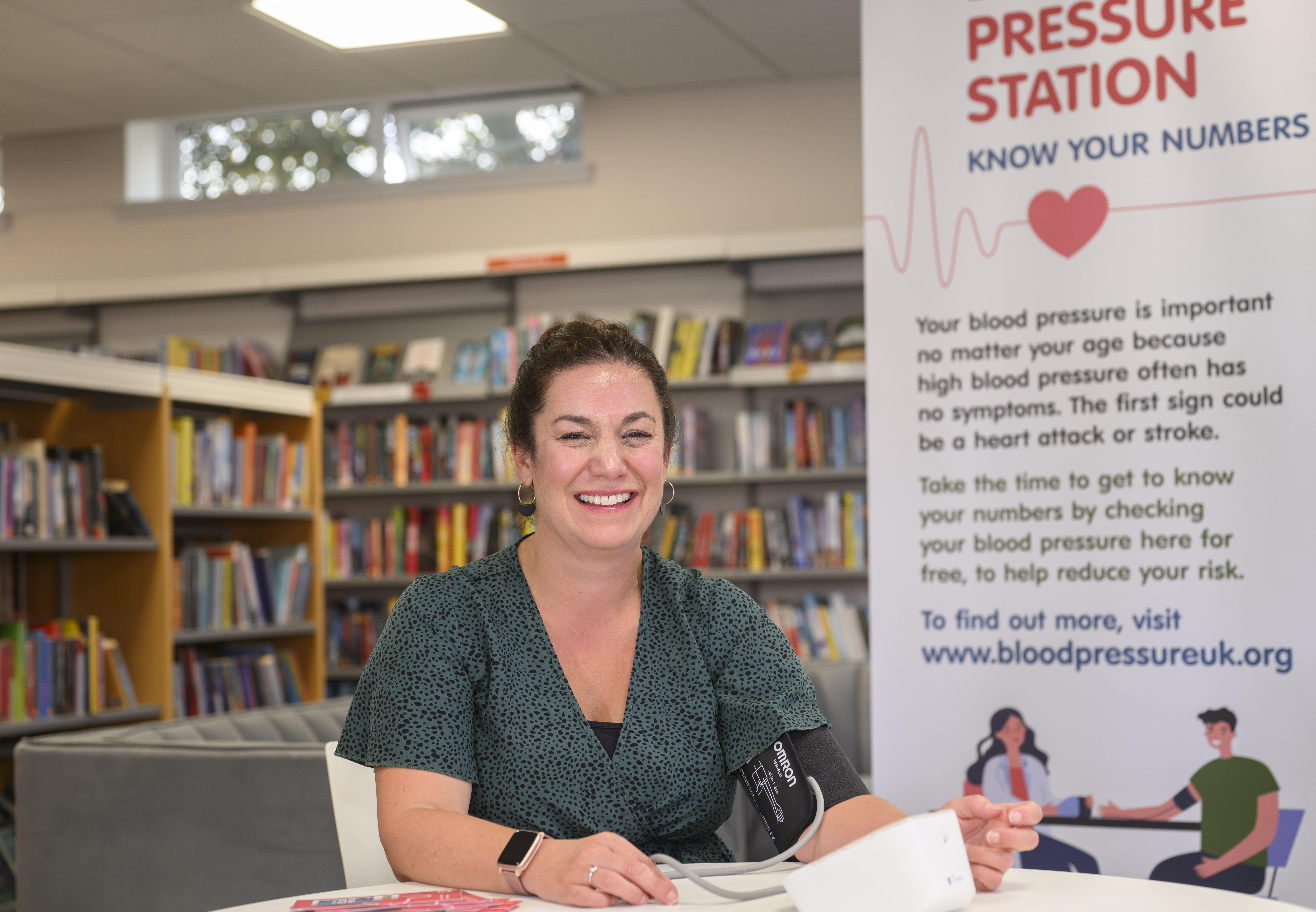 Adult sitting at a desk having their blood pressure taken