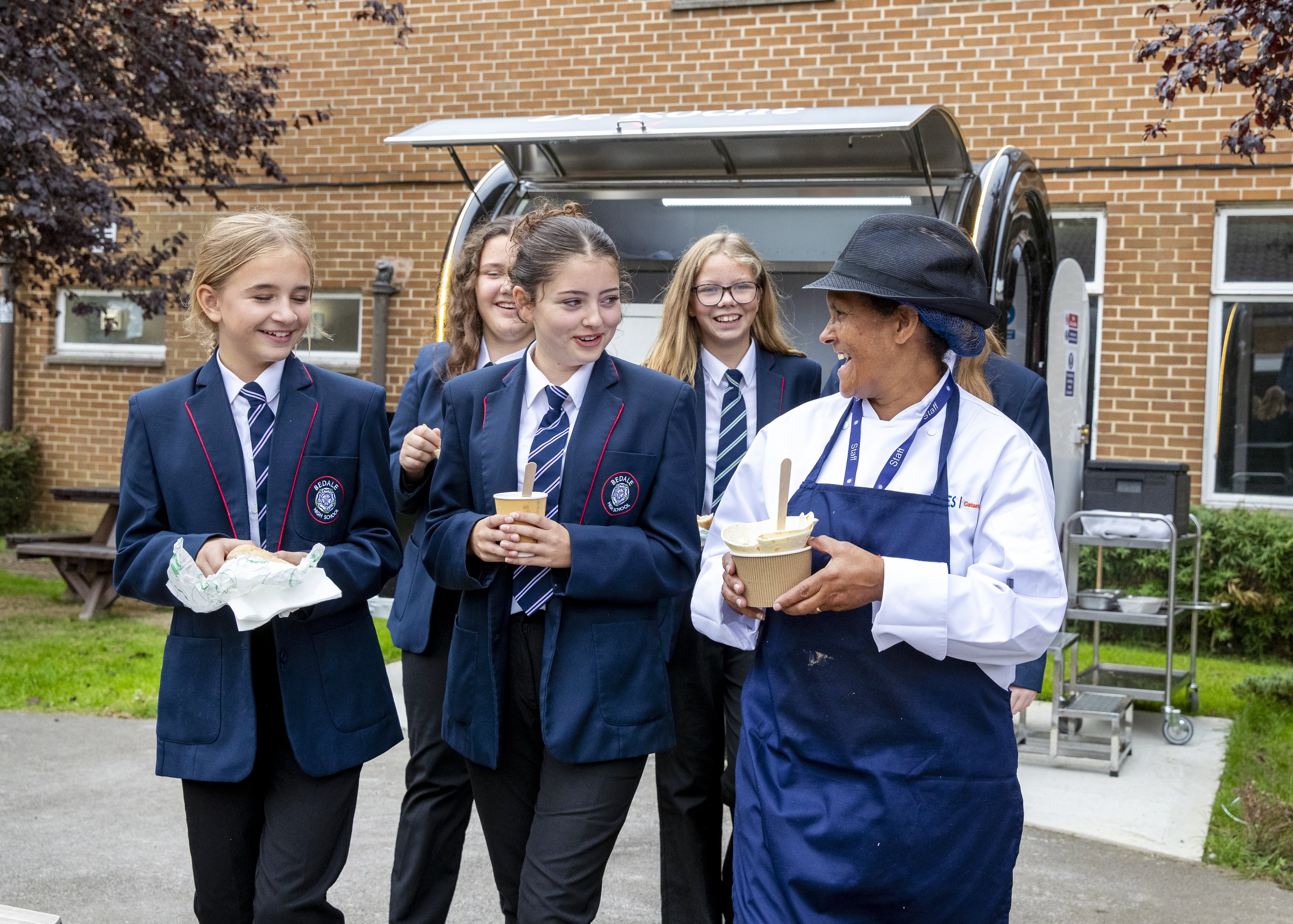 Group of school children with a school staff member carried food from the school food truck