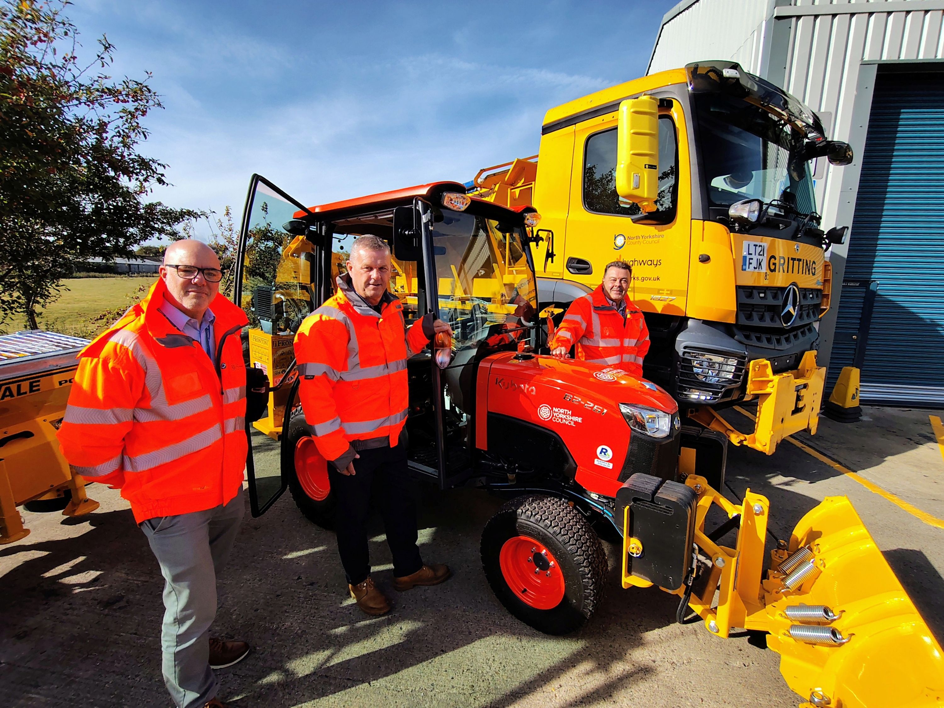 Three men with a gritter and tractor 