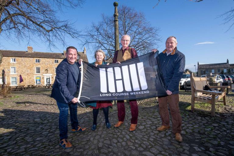 from left to right, Long Course Weekend’s founder and chief executive, Matthew Evans, Flo Grainger, owner of the Old Station Caravan Park, Masham Parish Council vice-chair, Ian Johnson, North Yorkshire Council’s executive member for open to business, Cllr Derek Bastiman pictured with the Long Course Weekend flag in Masham.