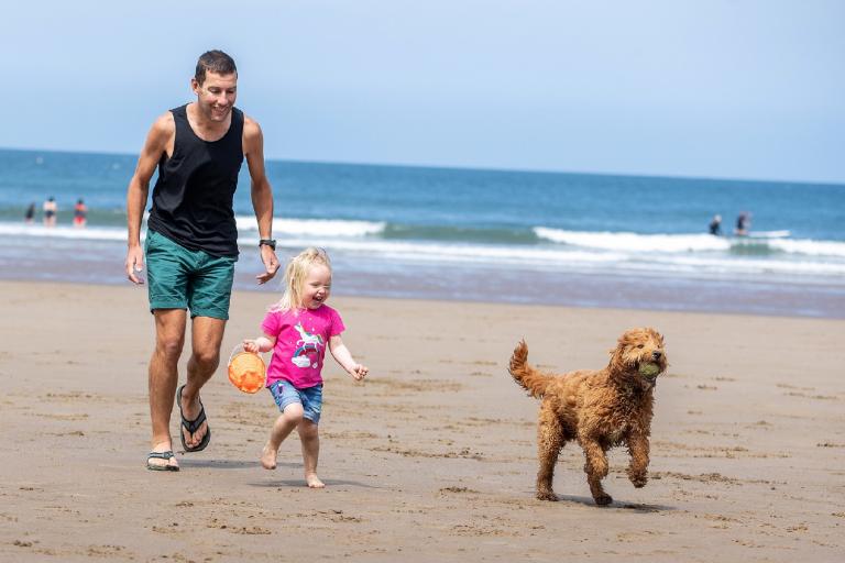 A man, young child and dog in a beach. Credit: Charlotte Graham
