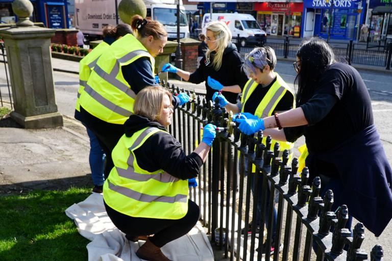 Six people painting a fence
