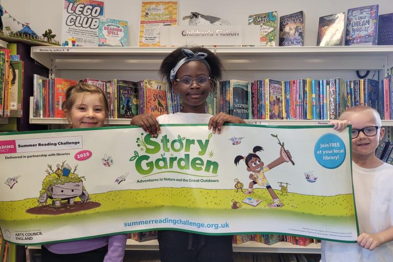 Three children holding a Summer Reading Challenge banner 