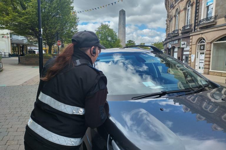 A person looking at a blue badge on a car