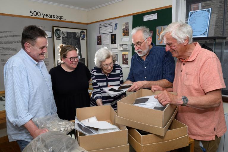 Four people looking at objects in a box