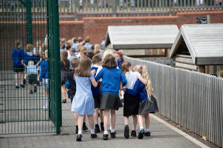 Young children walking into school with a blue uniform