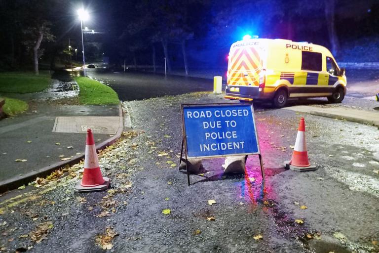 A road closure sign and police van
