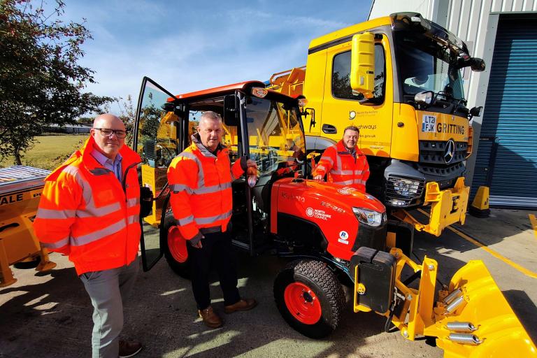 Three men with a gritter and tractor 