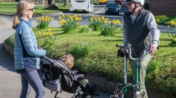 A lady with a buggy stood with a man holding a bike