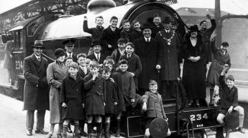 An old photo of a group of people with a stream train
