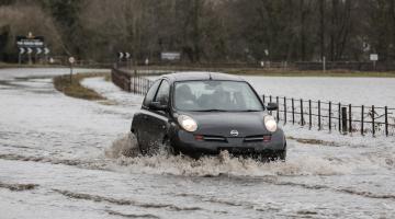 A car driving through flood water on a road in Masham.