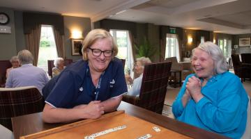 Resident and staff playing dominoes