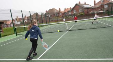 Children playing tennis outdoors.