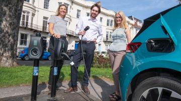 3 people with an electric car and charger