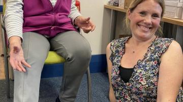 Library user Kay Piper tries on a pair of slippers with Caroline McCarthy