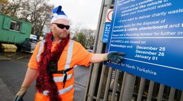 A person in front of the HWRC opening times sign