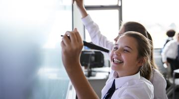 School students writing on a whiteboard