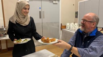 Sonia Omari serving home-made Afghan cuisine to ing ePeter Creek at the pop-up dinvent at Embsay Village Hall.