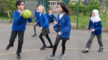 School children playing with a ball in a play ground