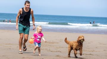 A man, young child and dog in a beach. Credit: Charlotte Graham