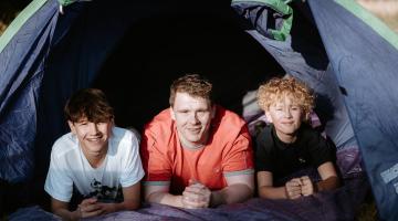 Three boys in the entrance to a tent