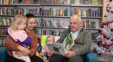 Two adults and a child reading in a library