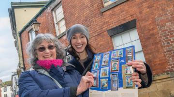 Cllr Hannah Gostlow who represents the Knaresborough east division with the chair of Knaresborough Renaissance at the window trail with picture of Queen Philippa by Ray Mutimer in window behind them.