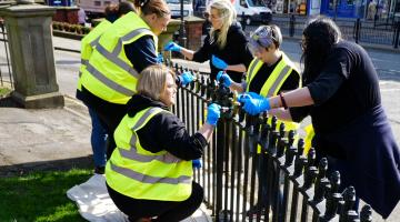 Six people painting a fence