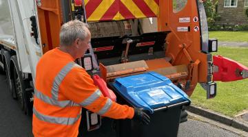 A bin man loading a bin onto a bin lorry