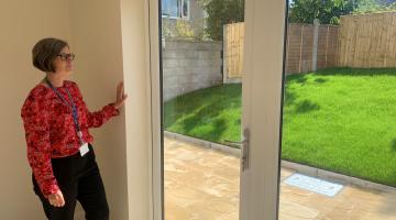 A lady looking out patio doors in towards a garden