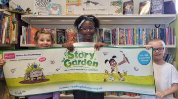 Three children holding a Summer Reading Challenge banner 