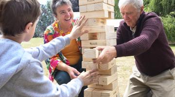 Two older people and young child playing Jenga